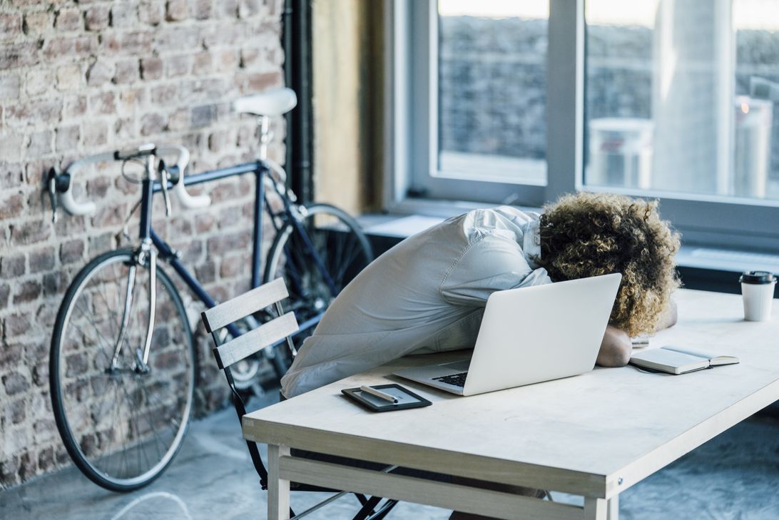 An office worker with head down on a work table.