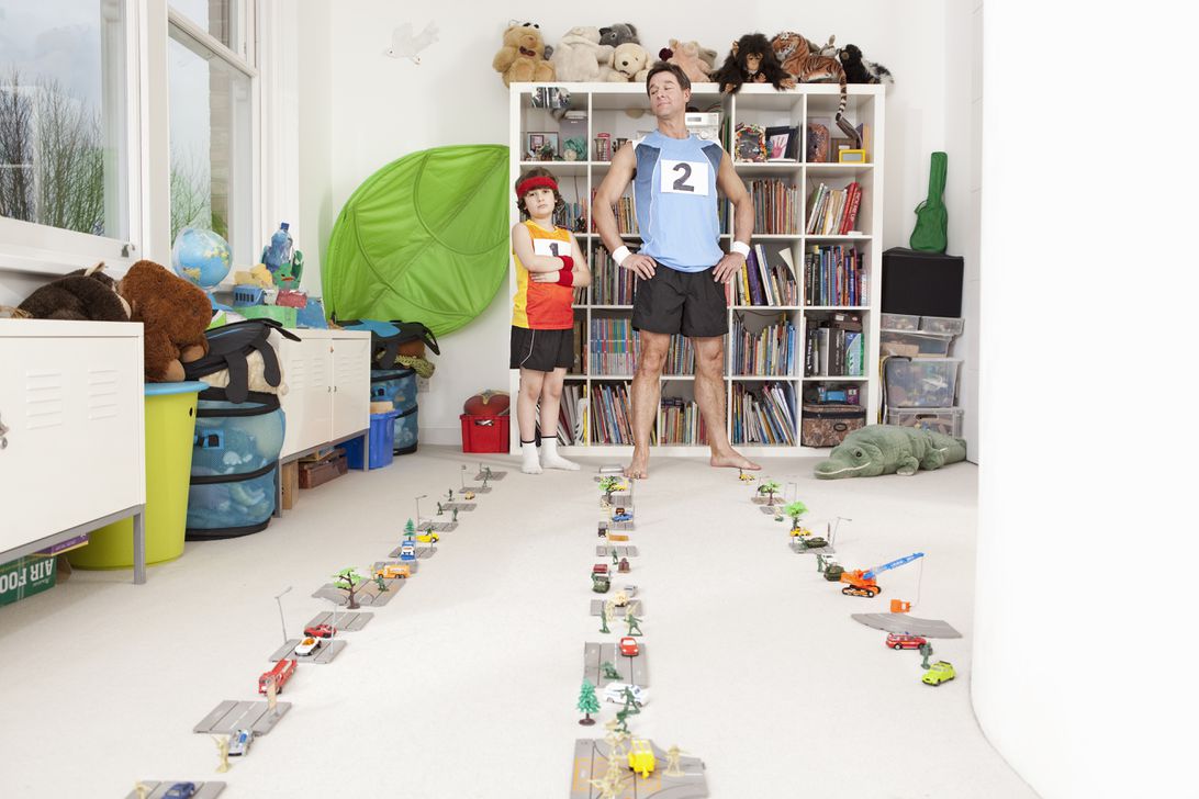 Comic image of a father and son getting ready to race amid toys in a child's room.
