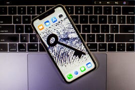 A smartphone on top of a laptop with the smartphone screen showing a key and a fingerprint.