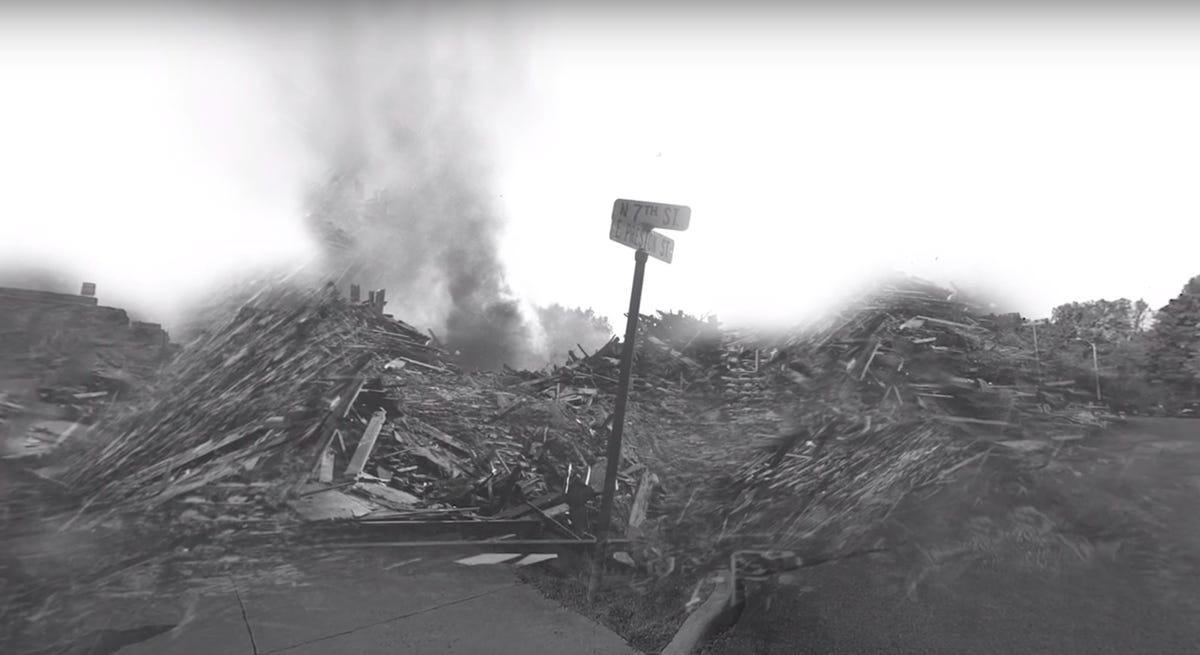 Piles of rubble, some smoldering, with street signs showing the intersection of N. 7th and E. Preston streets
