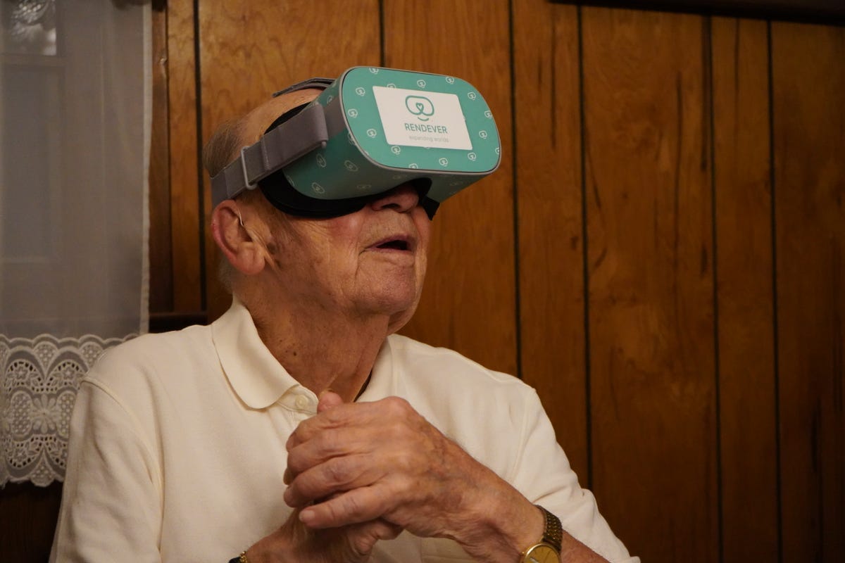 An older man wears a VR headset and looks on in wonder