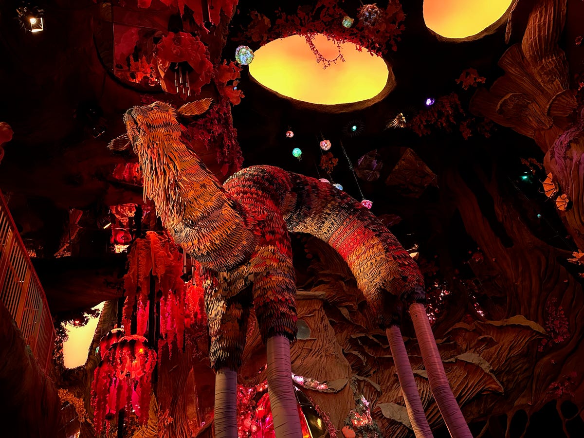 A massive furry art creature sculpture in a dim jungle world room