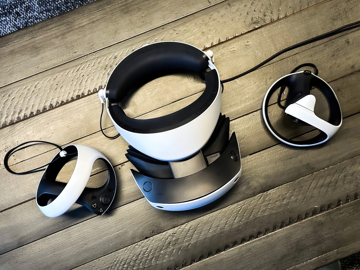 The PlayStation VR 2 headset and controllers seen from above on a wooden table.