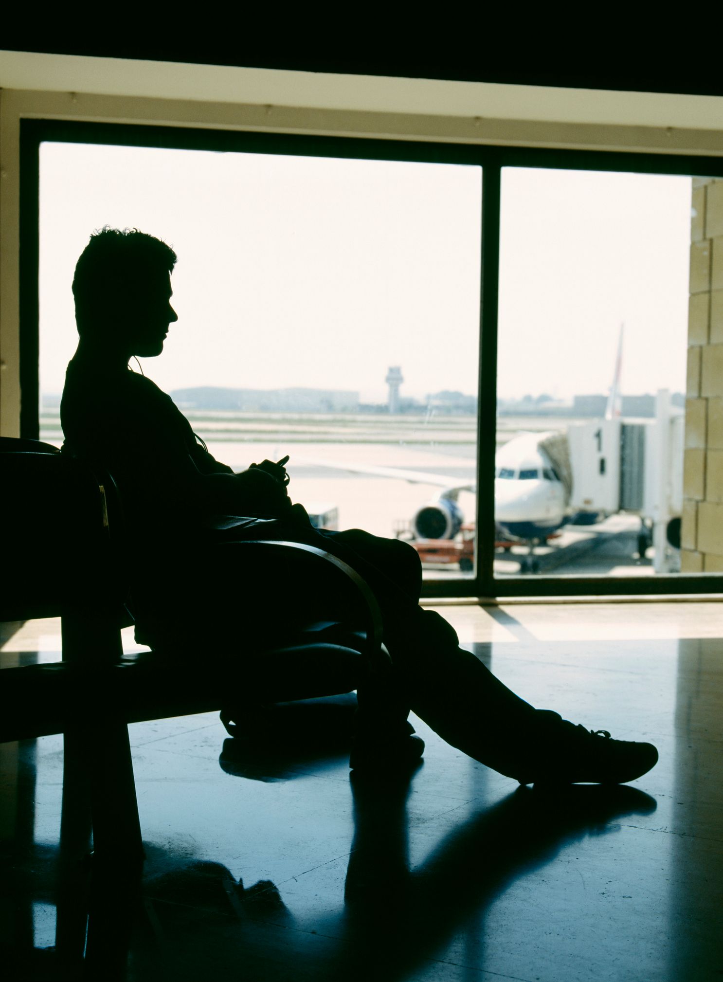 Image may contain Airport Terminal Silhouette Adult Person Clothing Footwear Shoe Sitting Pants and Aircraft